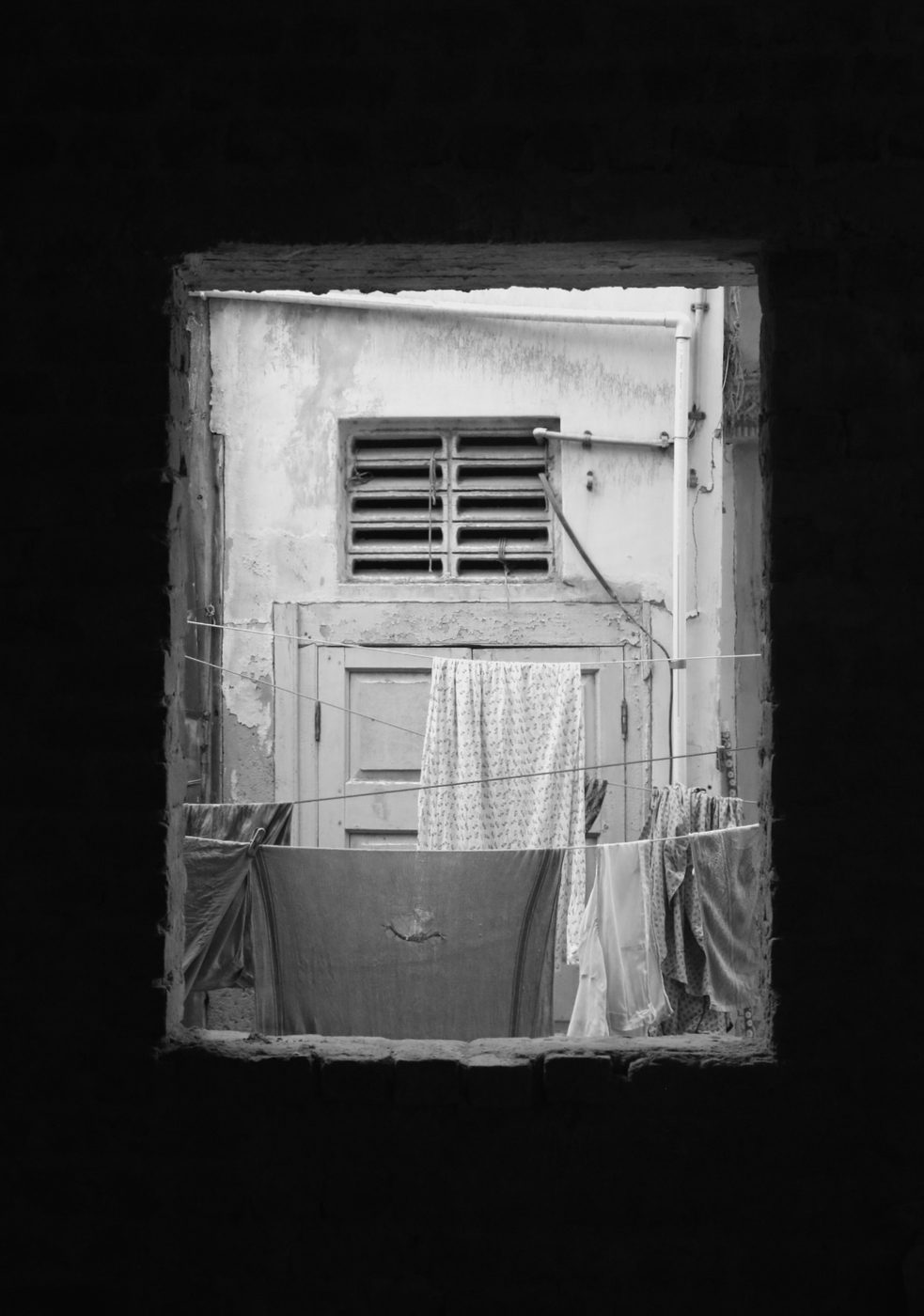 Laundry drying in a pol courtyard, seen through a window